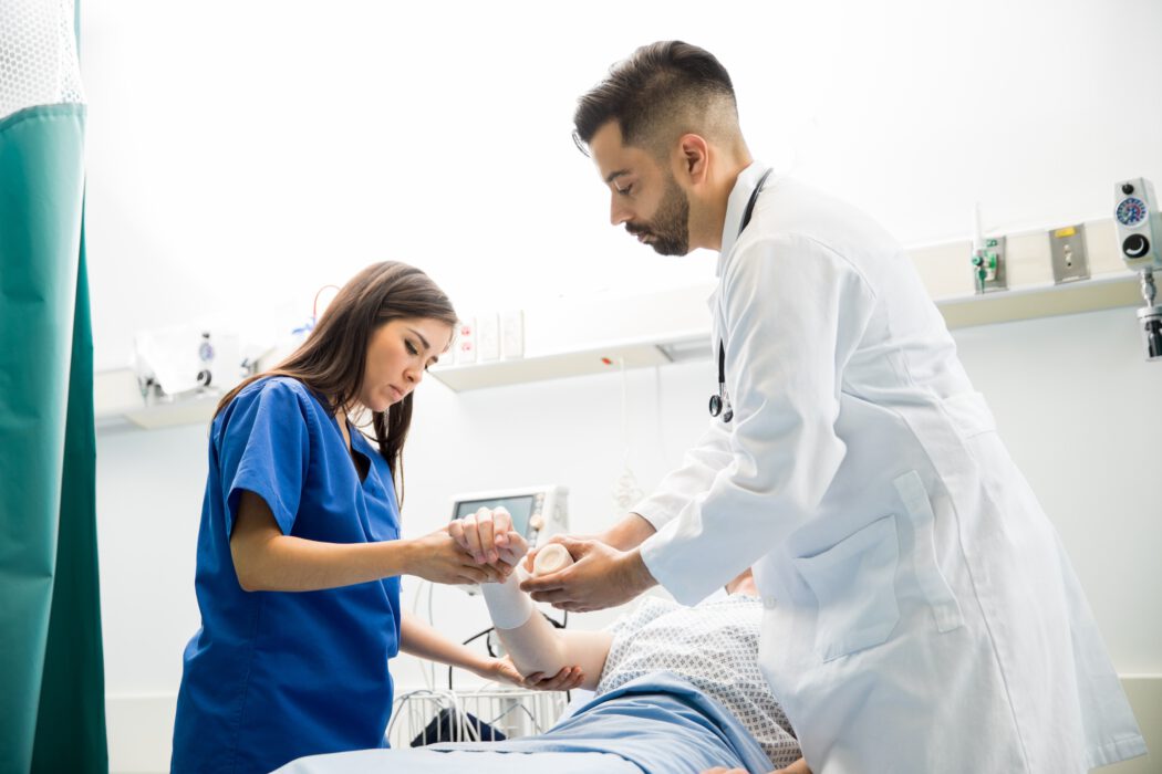In a Minnesota hospital room, a doctor and nurse from EPPA Health closely examine a patient's arm, with medical equipment visible in the background.