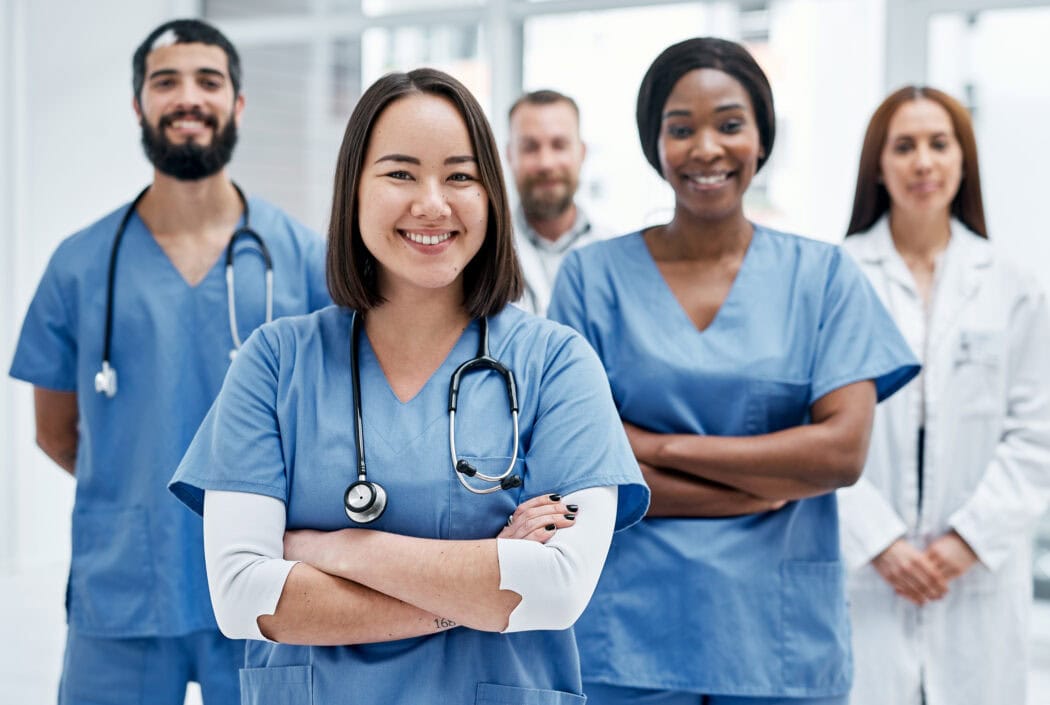 A group of emergency room physicians in blue scrubs and lab coats stand smiling in a well-lit medical facility, showcasing the expertise and dedication synonymous with Minnesota hospitals.