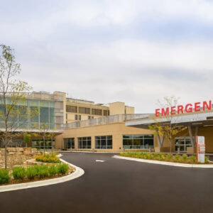 The EPPA Health emergency entrance features a large red "EMERGENCY" sign, surrounded by landscaped gardens and a paved driveway under the typically cloudy Minnesota sky.