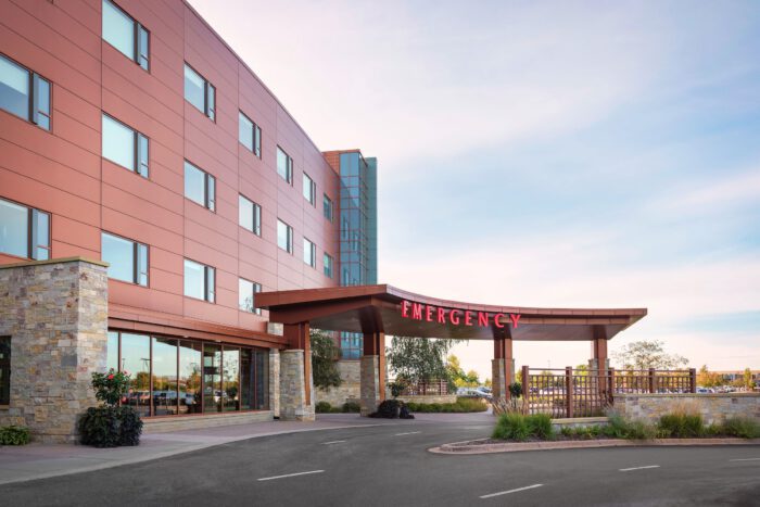 Exterior view of a hospital building, showcasing its iconic red "Emergency" sign above the entrance. Large windows on the upper floors reflect EPPA Health's commitment to excellence, making it one of the leading Minnesota Hospitals for specialized emergency room care.