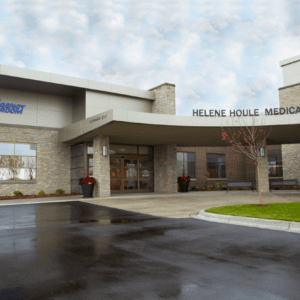 Exterior view of Helene Houle Medical Center showcases a modern stone facade and glass entrance, prominently displaying signage for the emergency room. As part of Minnesota Hospitals, it collaborates with EPPA Health to ensure skilled Emergency Room Physicians are always available.