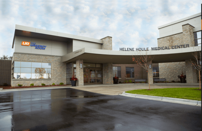 Exterior view of Helene Houle Medical Center showcases a modern stone facade and glass entrance, prominently displaying signage for the emergency room. As part of Minnesota Hospitals, it collaborates with EPPA Health to ensure skilled Emergency Room Physicians are always available.